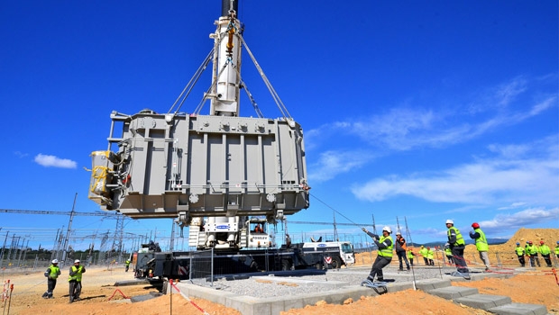Une grue performante et du personnel qualifié ont permis de positionner avec précision le transformateur de 87 tonnes sur son support qui recouvre la cuve de réception remplie de gravier.